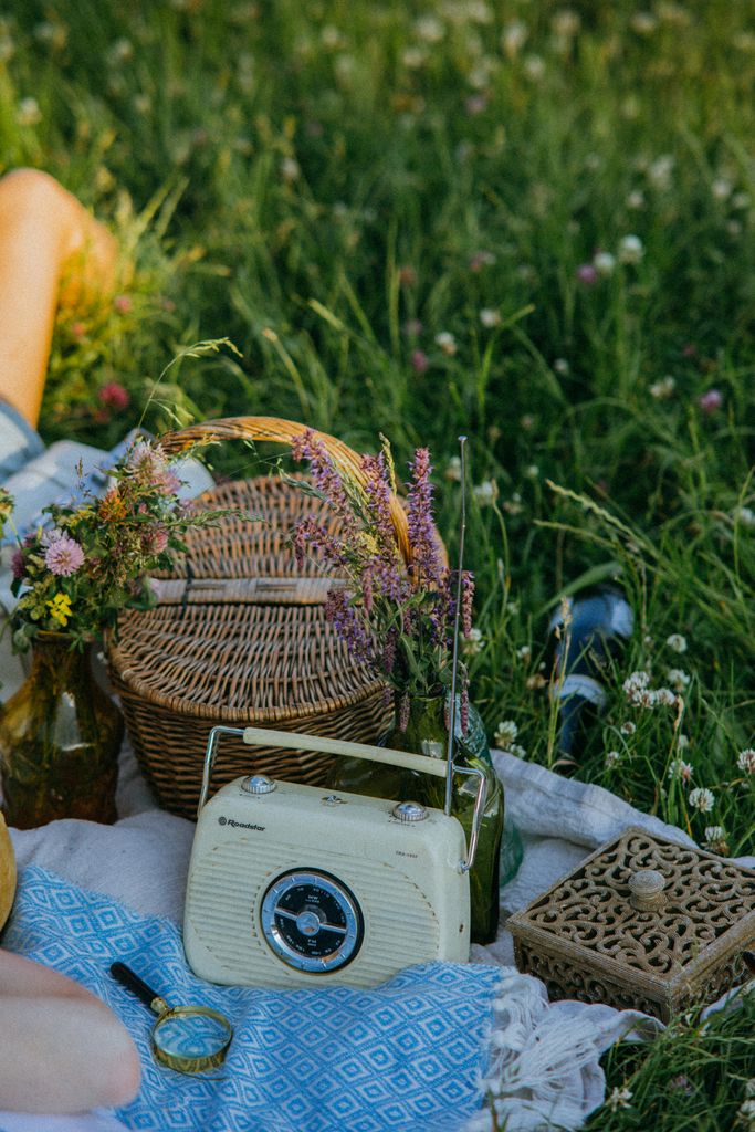 Charming outdoor picnic setup with vintage radio, basket, and wildflowers on a sunny day.